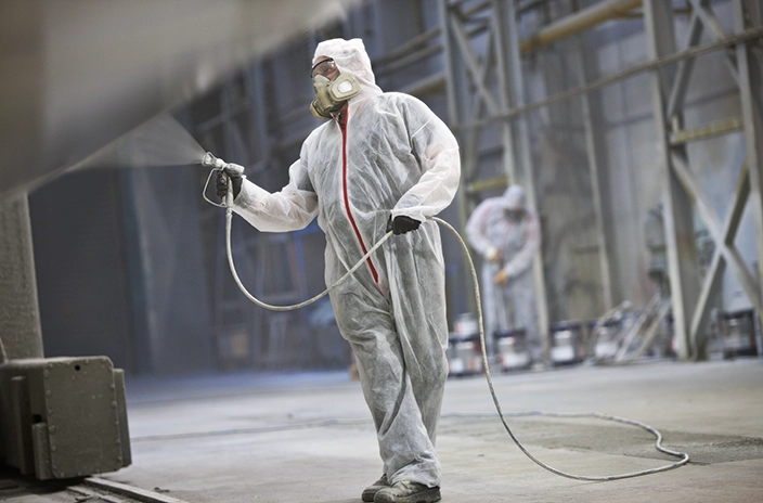 Man in white paint suit spraying